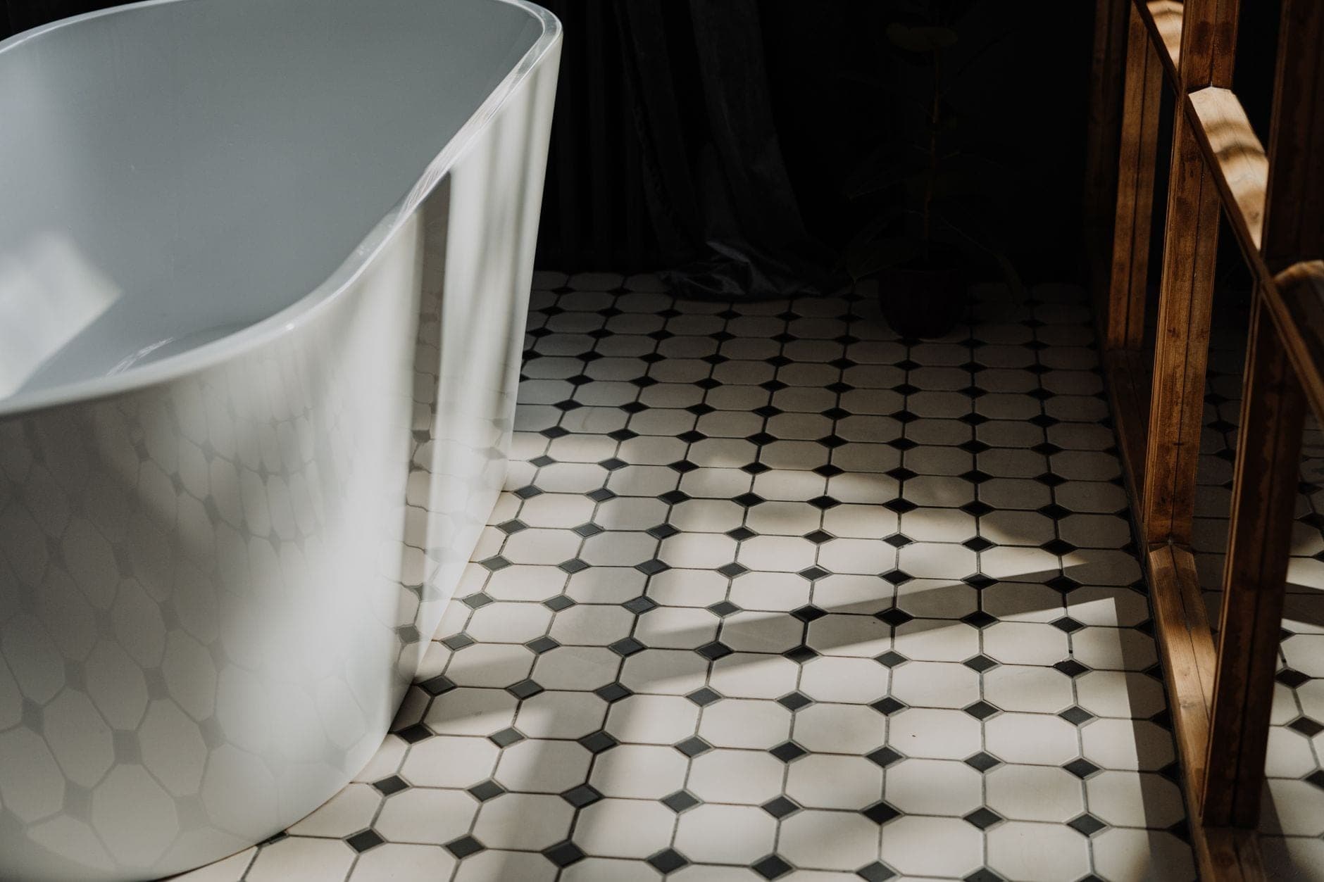 A cotton bath mat on a tiled bathroom floor beside a tub