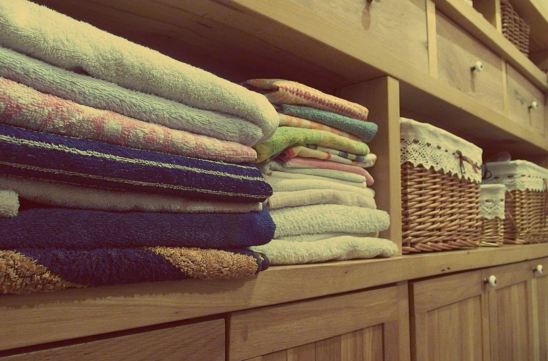 Folded cotton bath towels stacked on a wooden bathroom shelf