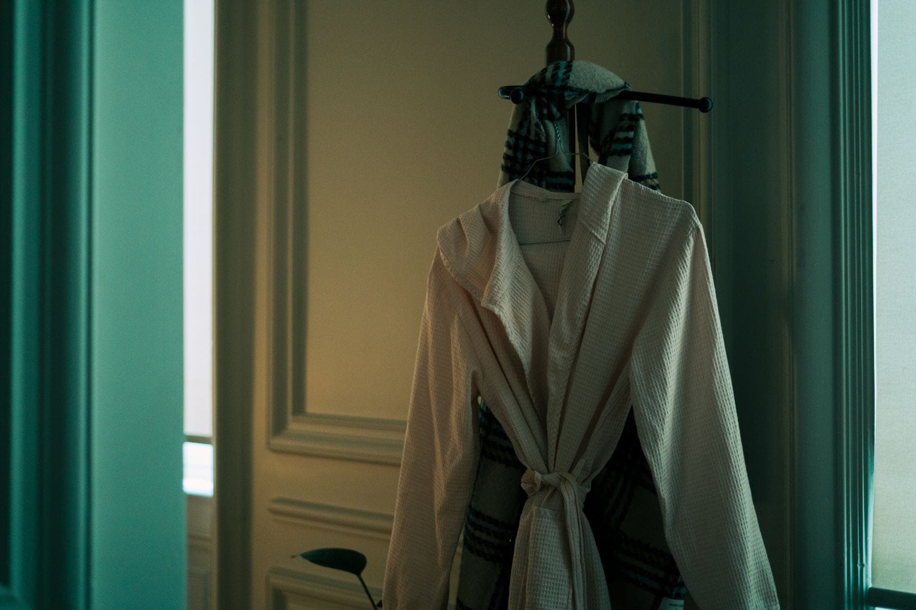 A cotton bathrobe hanging on a hook in a bright bathroom